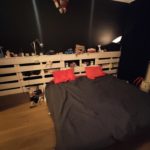 кровать из поддонов с красными подушками