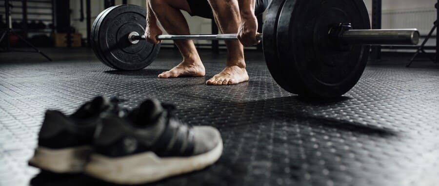 Атлет поднимает штангу на резиновом покрытии