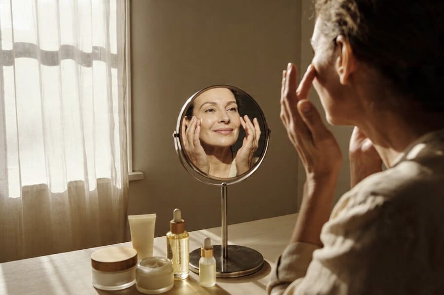 Женщина в возрасте 40 лет делает самостоятельный массаж лица у себя дома